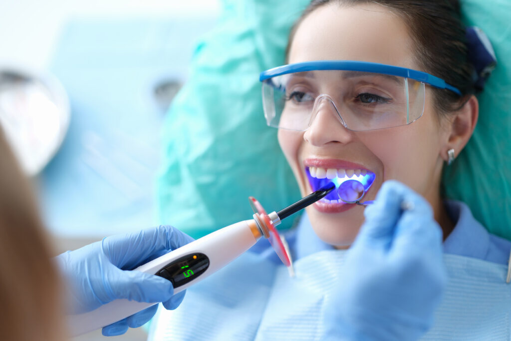 Dentist works with dental polymerization lamp in oral cavity